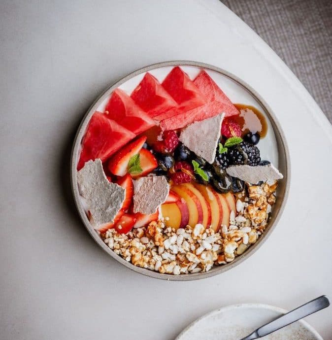 bowl of assorted fresh fruits and granola on a table